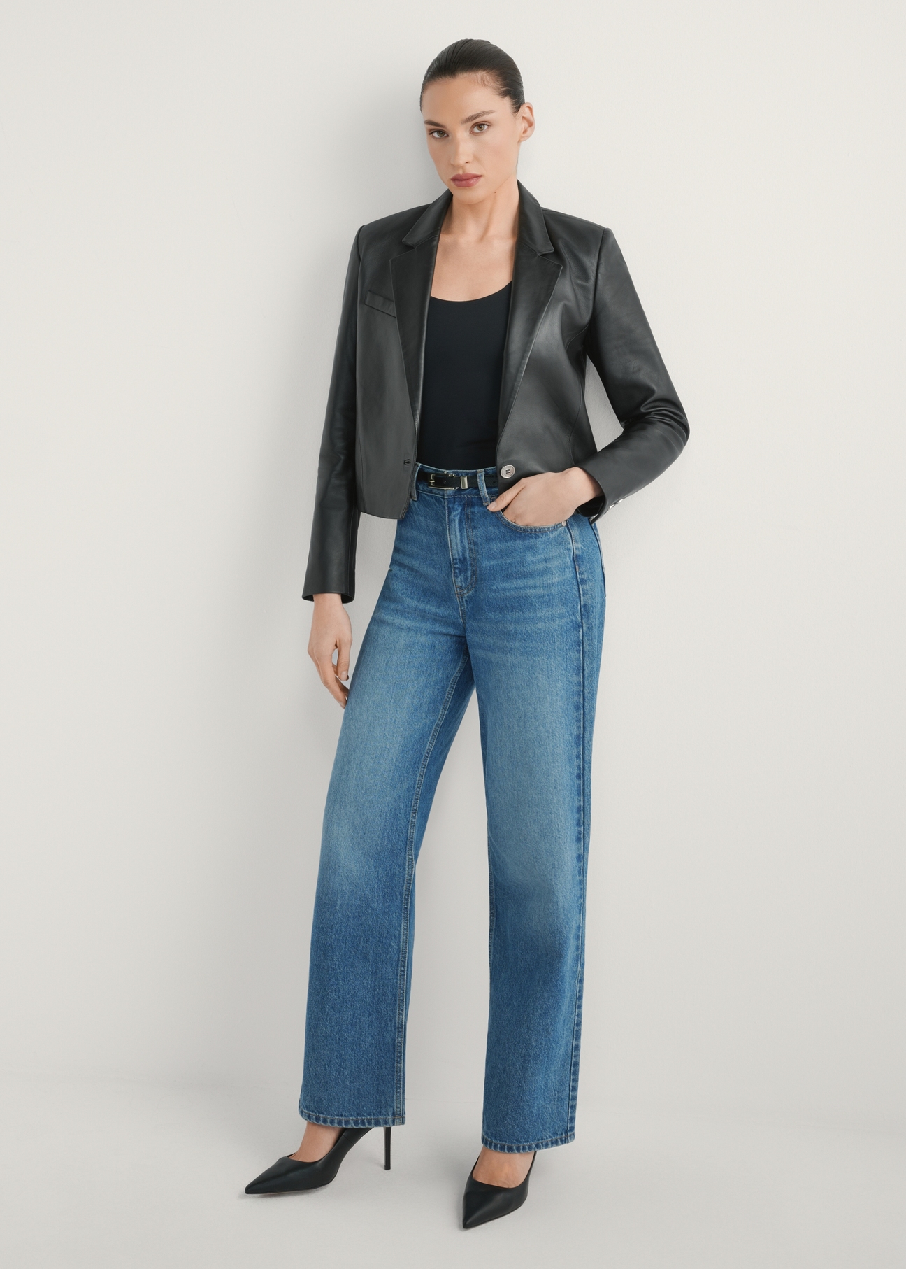 Dámska krátka kožená bunda KURDT-0522-99(W26) - pohľad spredu na výrobok, na modelke, na svetlom pozadí. Viditeľné celé telo.