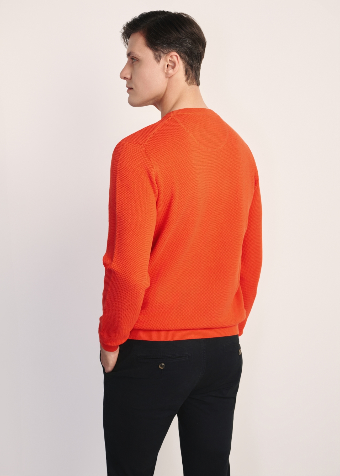 Oranžový pánsky sveter SWEMT-0181-30(Z25), pohľad na produkt zozadu na modeli. Viditeľná polovica siluety.