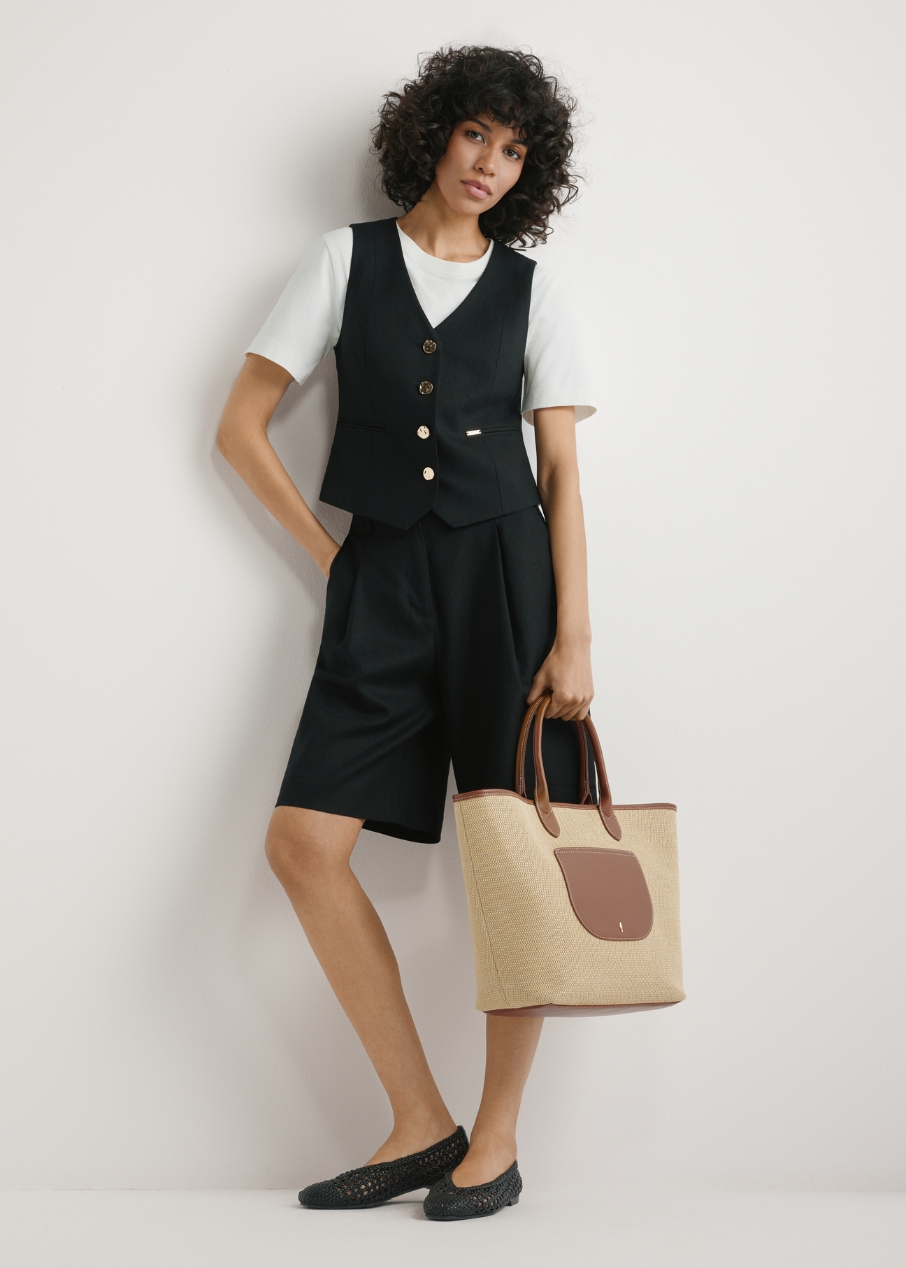 Veľká dámska slamená kabelka TOREC-1229-1E(W26), pohľad na produkt držaný v ruke modelky, na svetlom pozadí. Viditeľná je celá silueta.