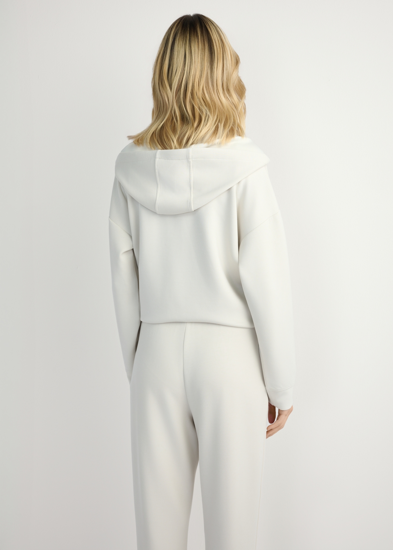 Svetlobéžová dámska mikina s kapucňou BLZDT-0111A-1A(W26), pohľad na modelku zozadu. Viditeľná polovica siluety.