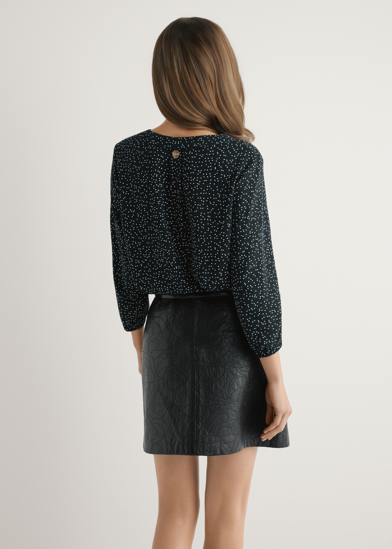 Dámska bodkovaná blúzka BLUDT-0172A-9P(W26) - pohľad na výrobok zozadu, na modelke, na svetlom pozadí. Viditeľná polovica siluety.