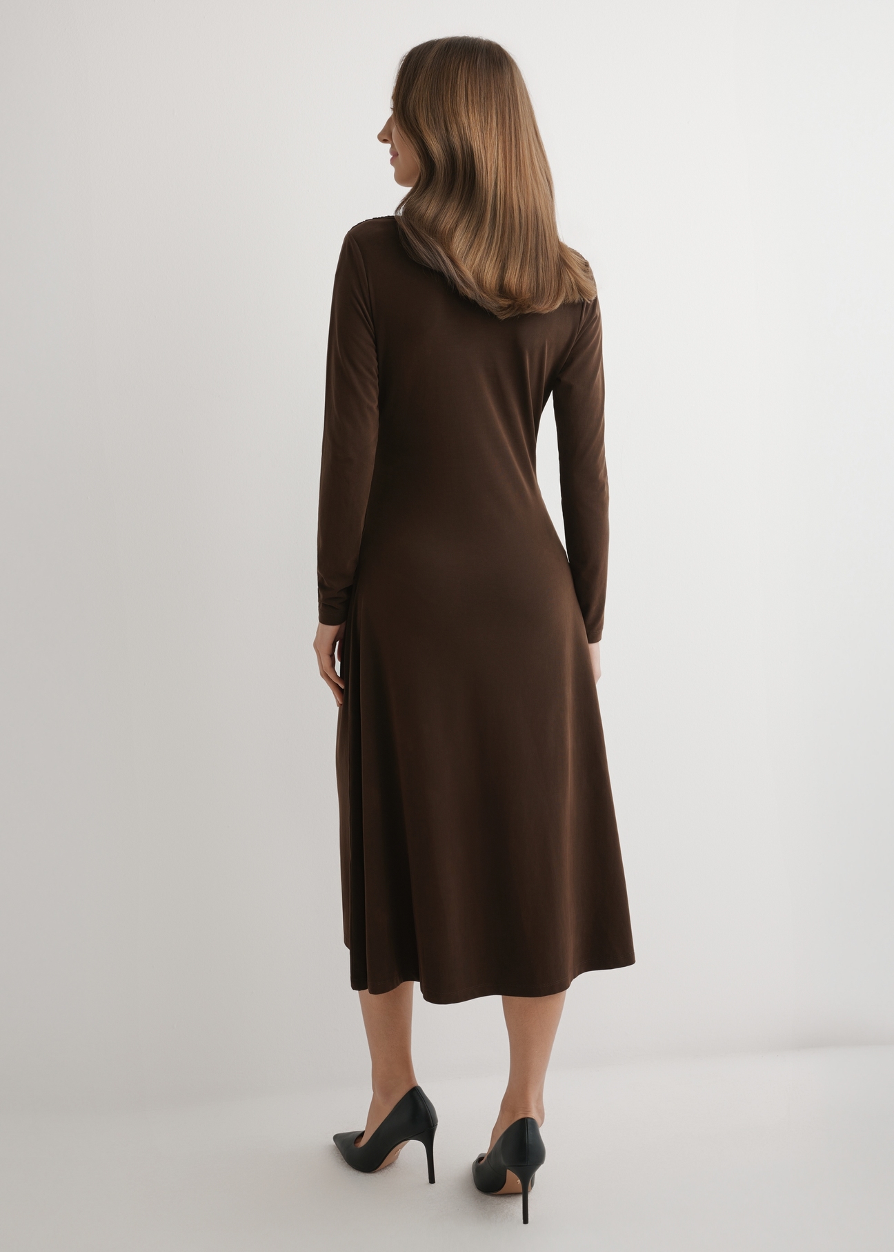 Hnedé modálne midi šaty SUKDT-0259-1I(W26) - pohľad na výrobok zozadu na modelke na svetlom pozadí. Viditeľná je celá silueta.
