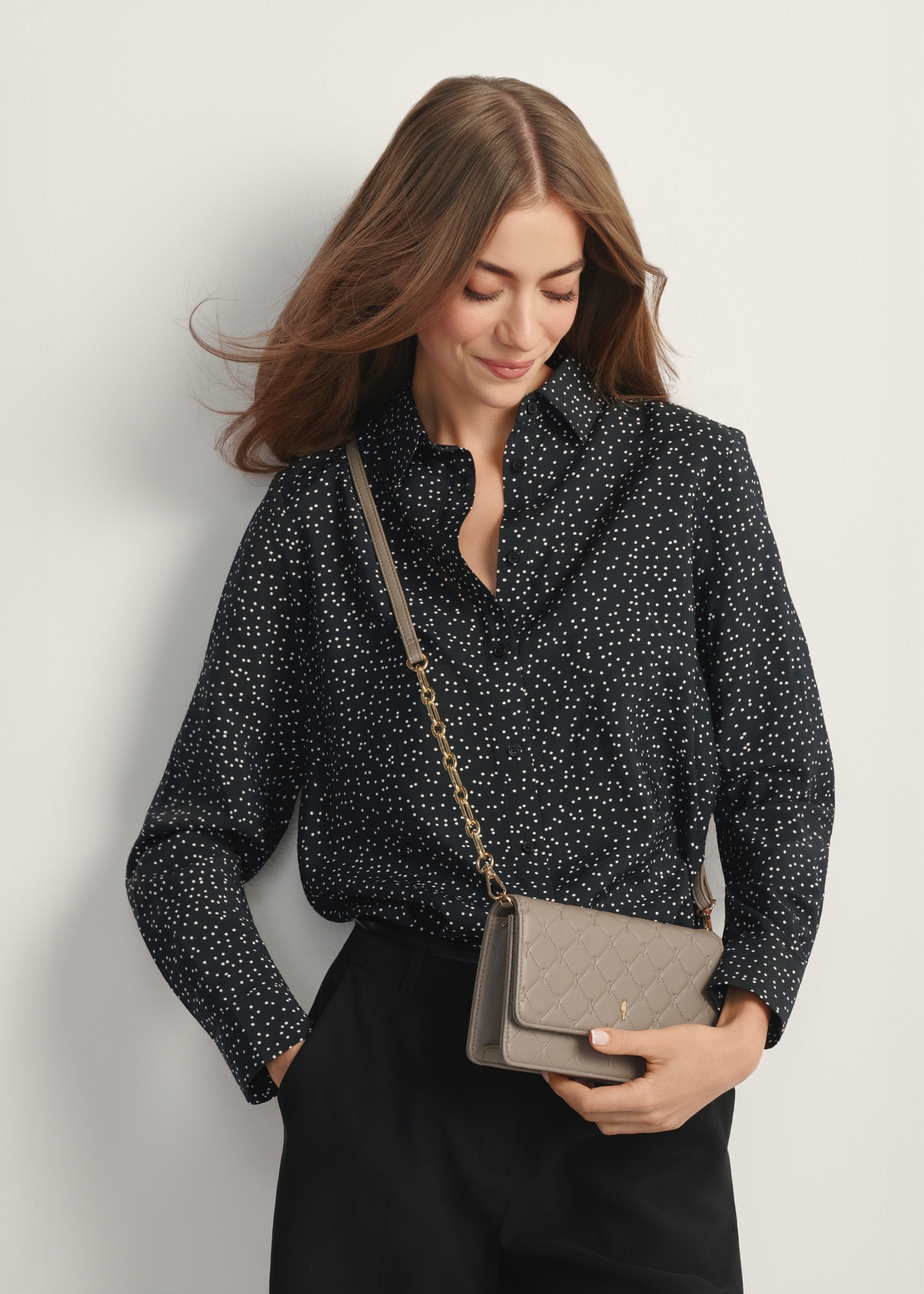 Malá dámska kabelka v chladnej hnedej farbe TOREC-1178-1K(W26) - pohľad spredu na produkt, na modelke, na svetlom pozadí. Viditeľná polovica siluety.