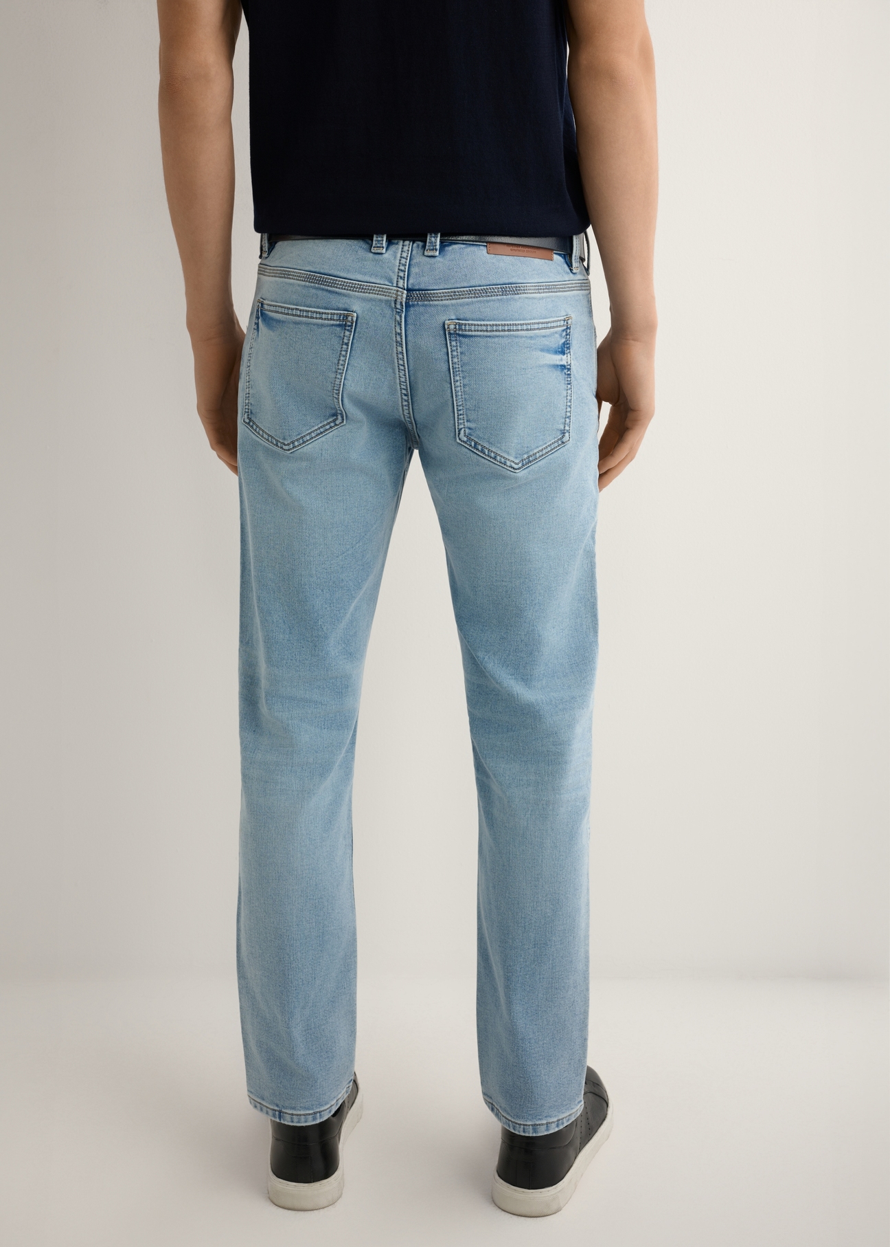 Pánske modré rifle JEAMT-0021-7B(W26), pohľad na produkt zozadu na modeli. Viditeľná polovica siluety.