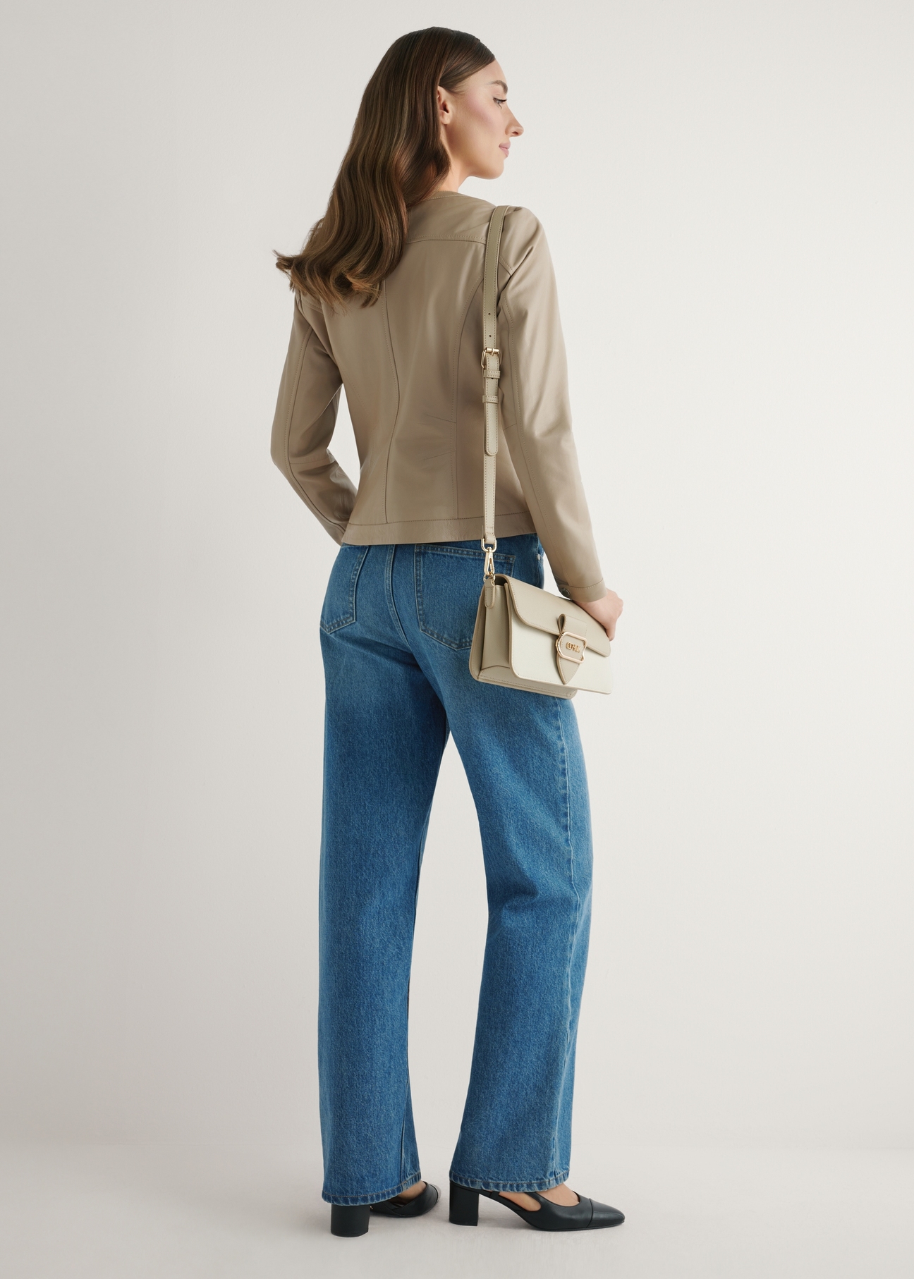 Dámska krémová kabelka cez rameno TOREC-1120-0P(W26) - pohľad na produkt mierne diagonálny, na modelke, na svetlom pozadí. Viditeľná je celá silueta.