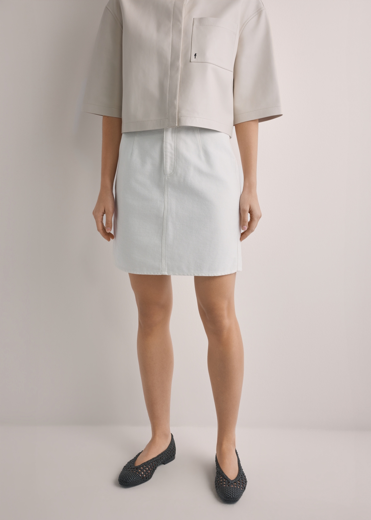 Krémová džínsová minisukňa SPCDT-0126-0B(W26), pohľad spredu na produkt na modelke. Viditeľná polovica siluety.