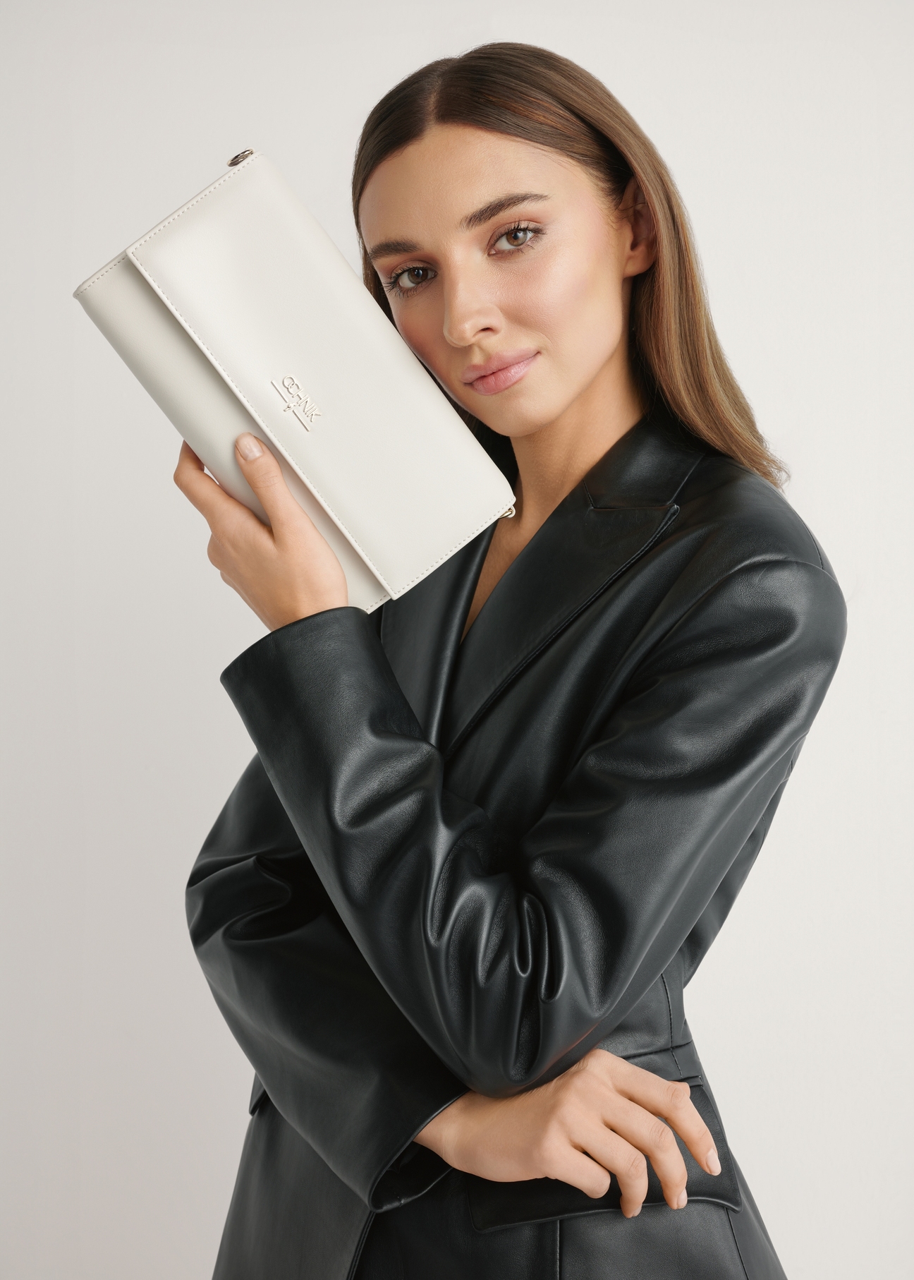 Krémová kabelka TOREC-1210-0B(W26) - pohľad na produkt držaný v ruke modelky na svetlom pozadí. Viditeľná polovica siluety.