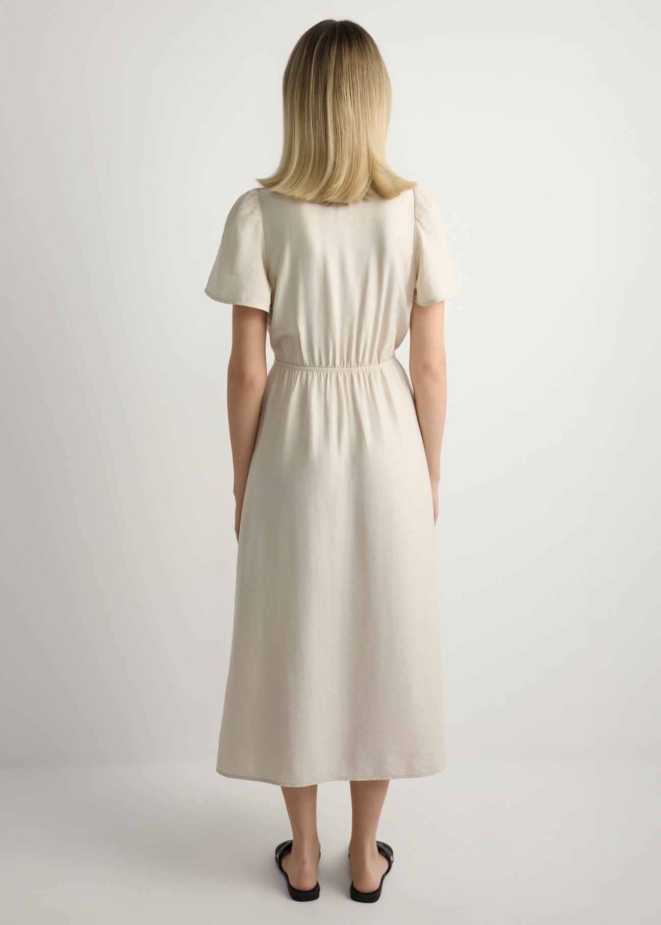 Dámske svetlé béžové šaty SUKDT-0255-1A(W26), pohľad na výrobok zozadu na modelke. Viditeľné celé telo.