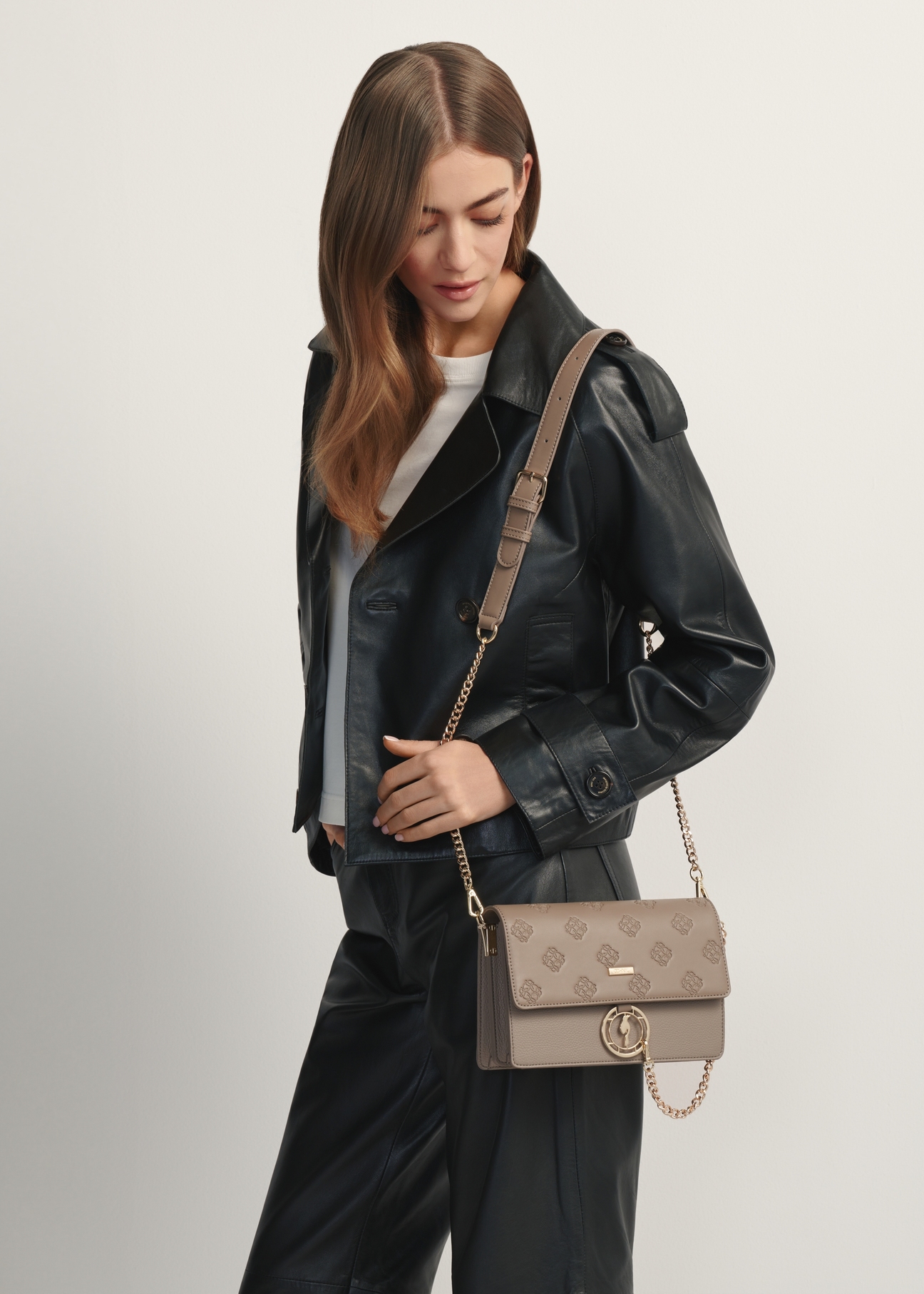 Dámska kabelka tmavo béžovej farby s monogramom TOREC-0536-1K(W26), pohľad spredu na produkt na modelke, viditeľná polovica siluety.