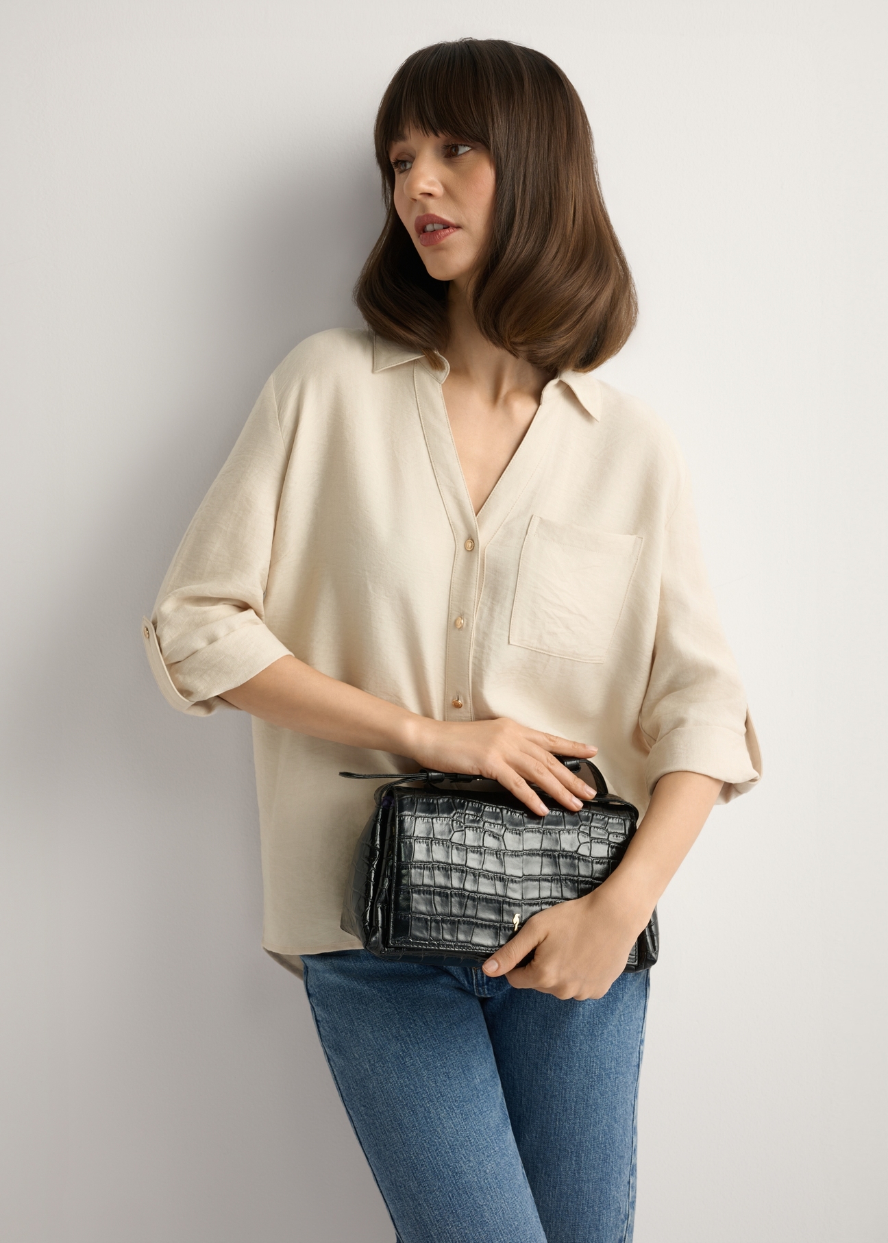 Dámska kožená kabelka TORES-1234-9G(W26) v čiernej farbe s krokodílím vzorom, pohľad na produkt spredu na modelke, viditeľná polovica siluety.