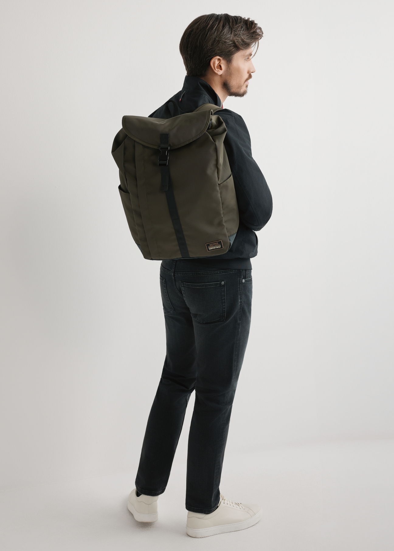 Khakifarbener Herrenrucksack TORMN-0415-8D(W26) – Vorderansicht des Produkts an einem Model vor hellem Hintergrund. Das gesamte Modell ist sichtbar.