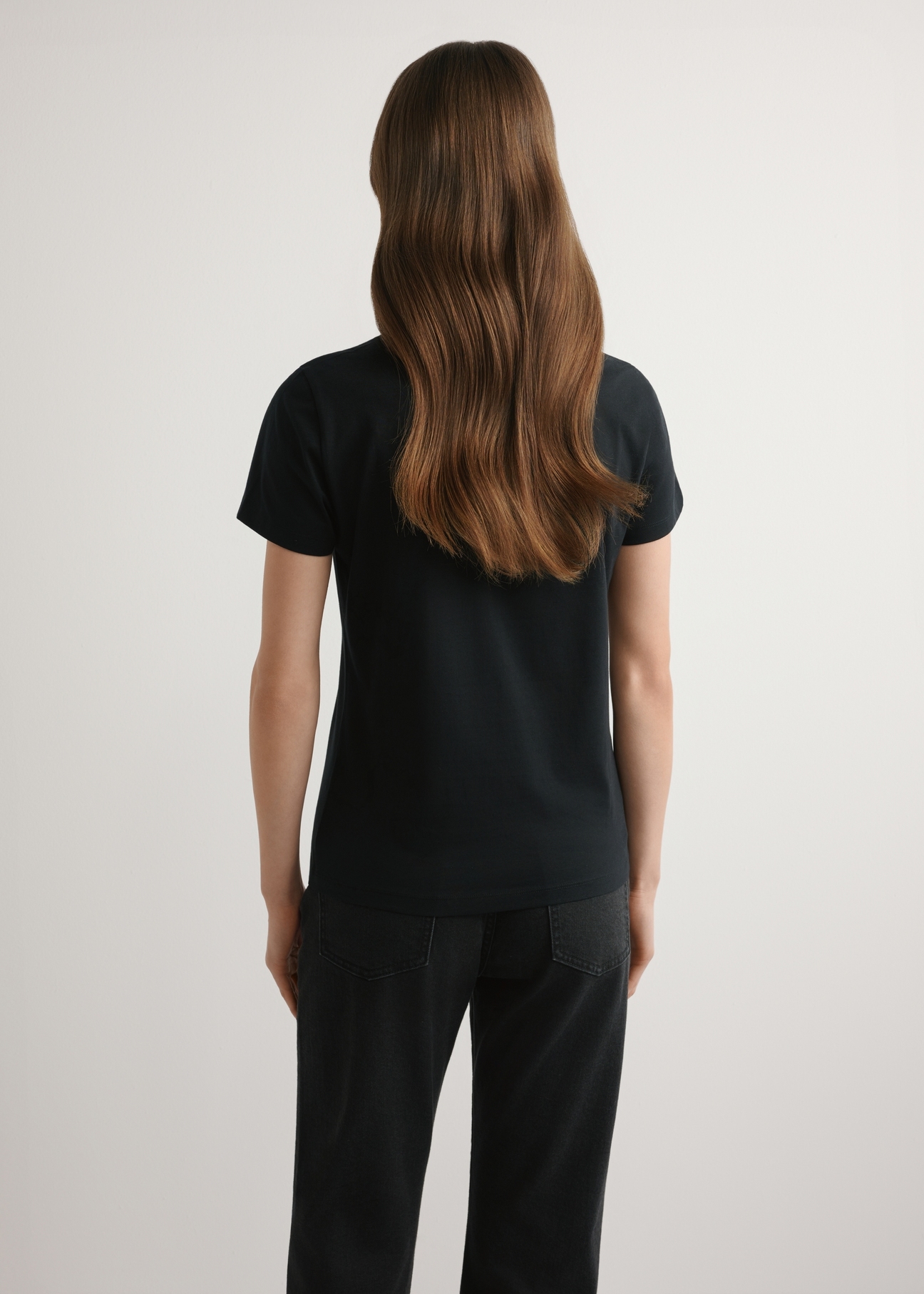 Čierne dámske tričko s logom TSHDT-0155-99(W26), pohľad na produkt zozadu na modelke. Viditeľná polovica siluety.