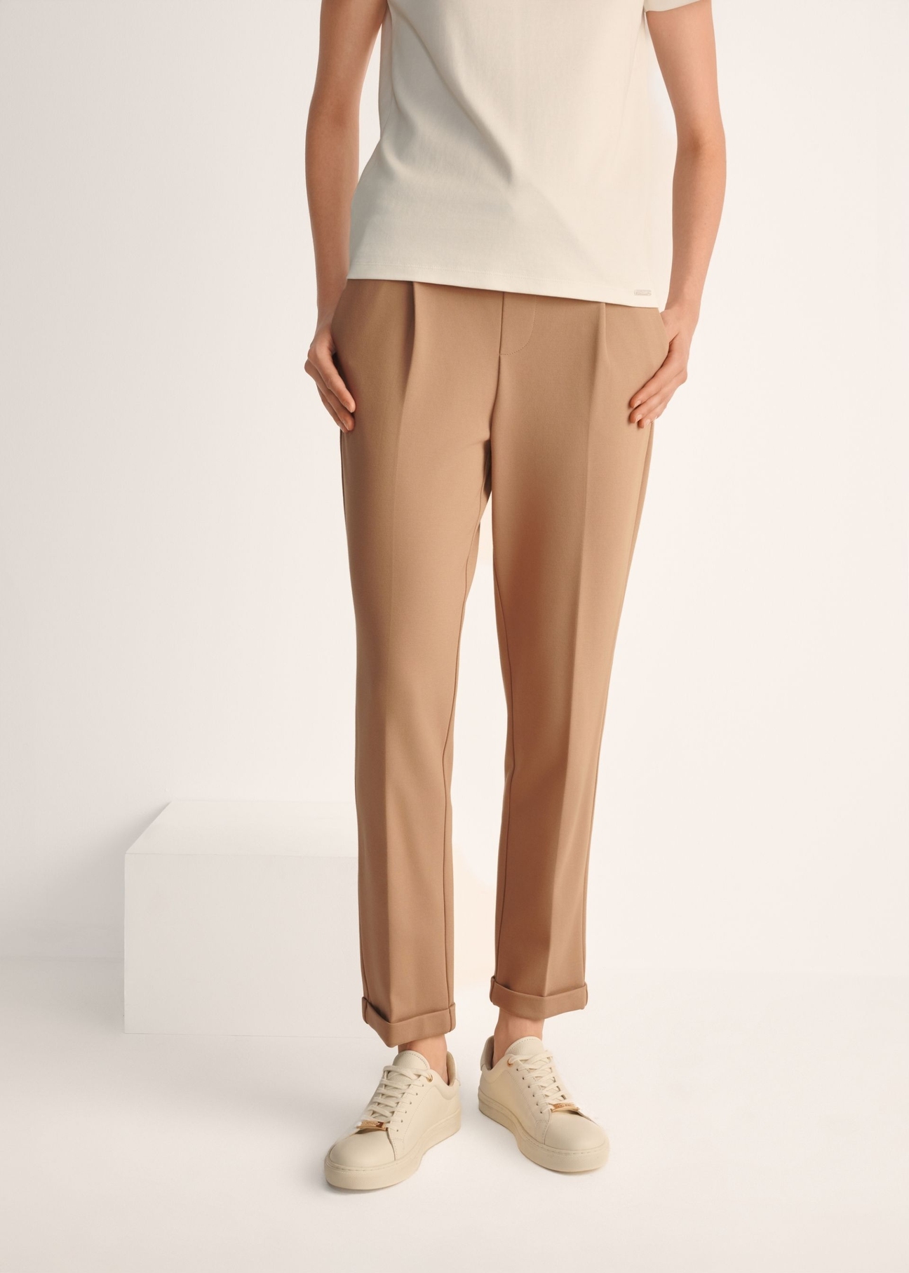 Dámske biele kožené tenisky BUTYD-1068-0B(W26), pohľad na produkt na nohách modelky na svetlom pozadí.