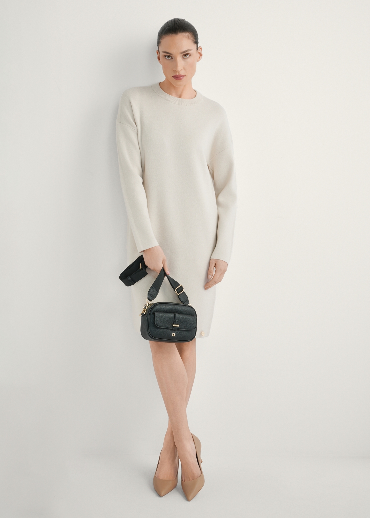 Malá čierna dámska kabelka TOREC-1174-99(W26), pohľad na produkt v ruke modelky. Viditeľné celé telo.