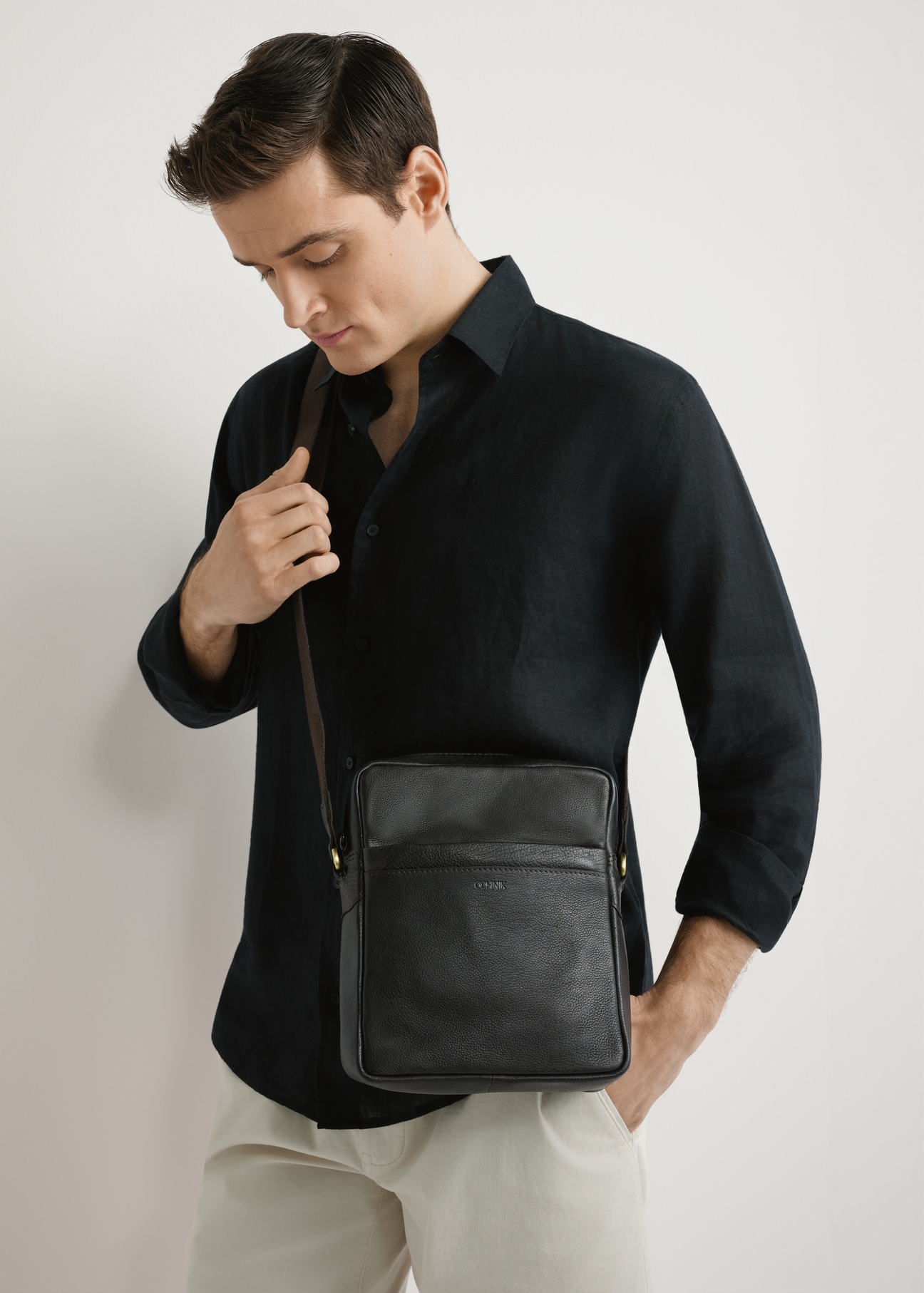 Pánska tmavohnedá kožená taška TORMS-0502-1I(W26) - pohľad spredu na produkt, na modeli, na svetlom pozadí. Viditeľná polovica siluety.