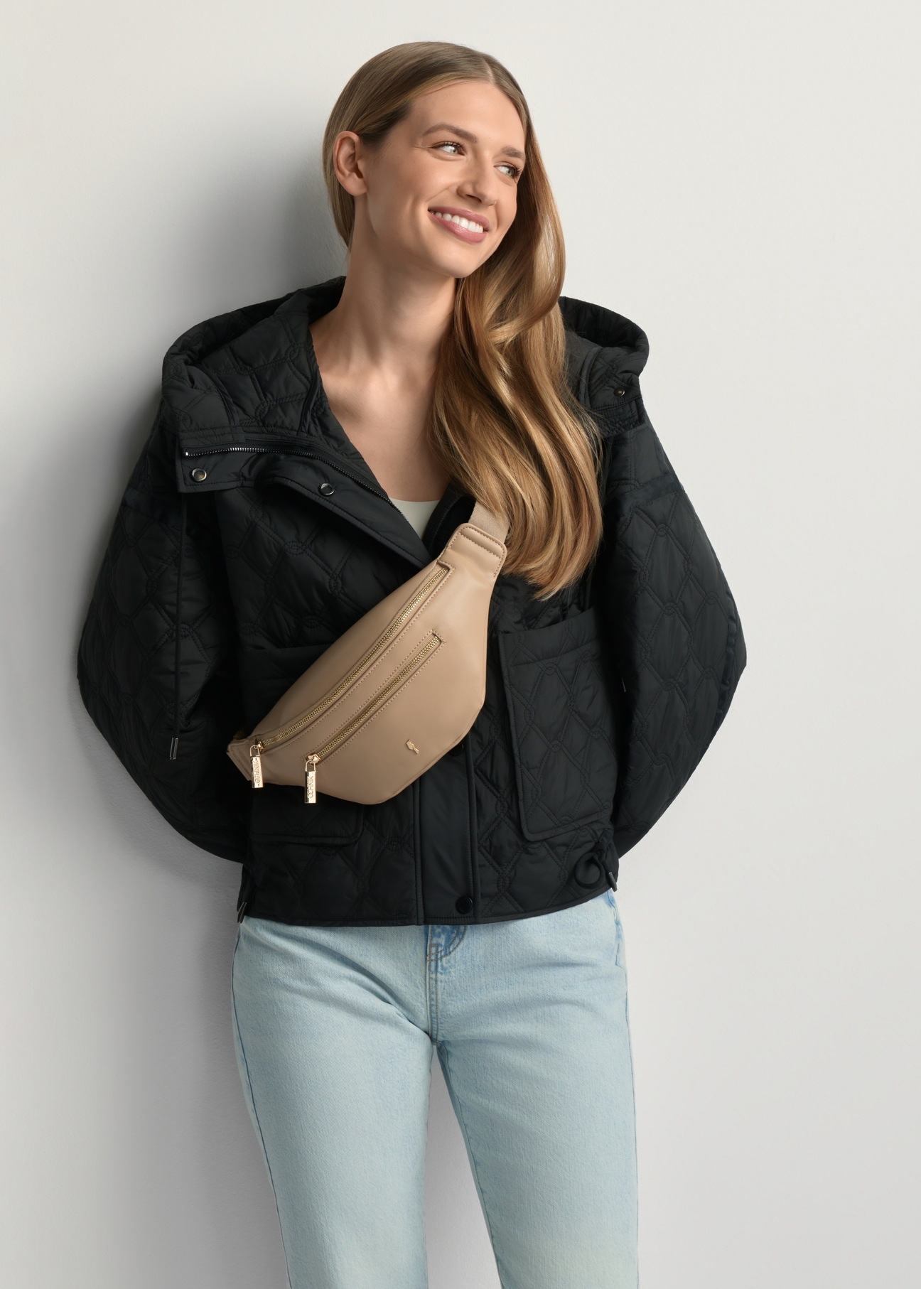 Beige Damen-Bauchtasche aus Kunstleder TOREC-1190-1A(W26) – Vorderansicht des Produkts an einem Model vor hellem Hintergrund. Die Silhouette ist zur Hälfte sichtbar.