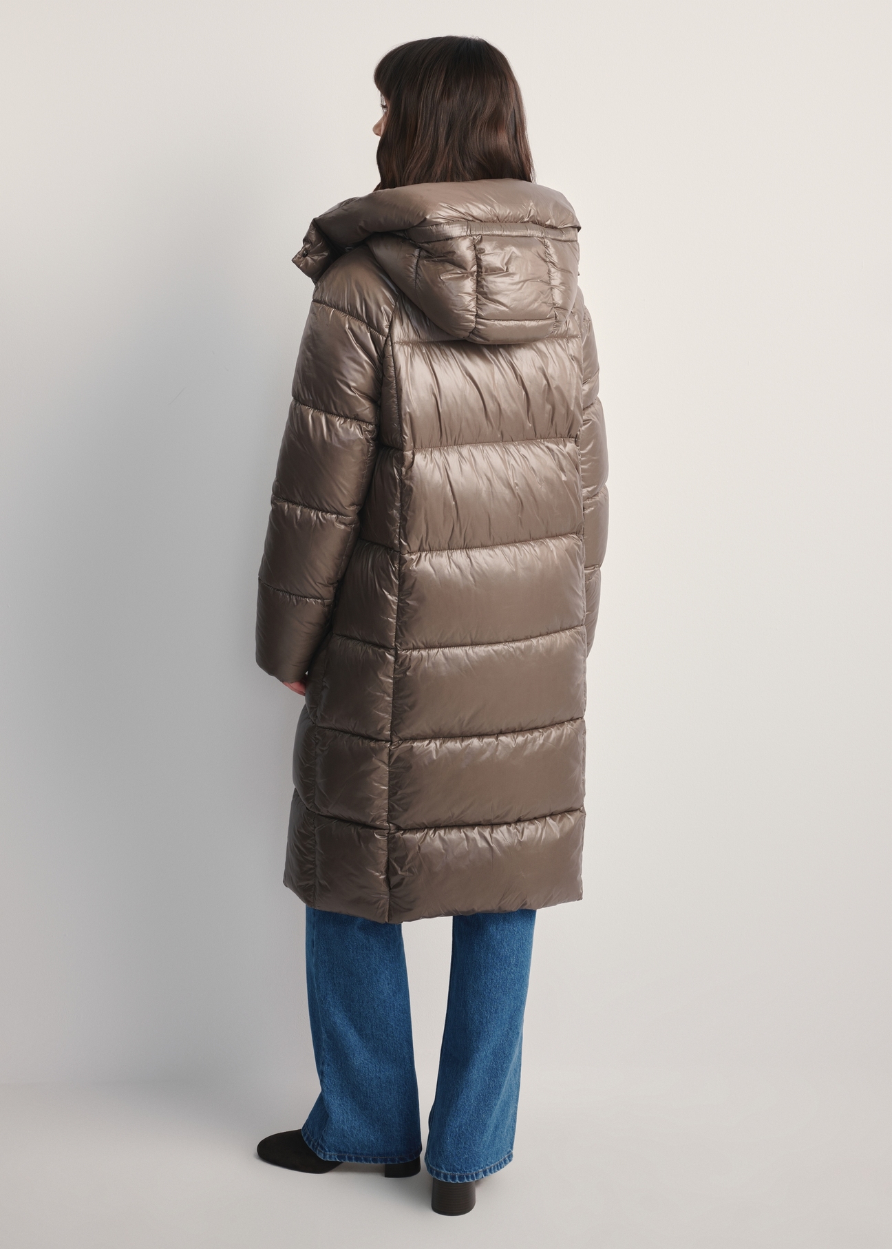 Dámska dlhá prešívaná bunda KURDT-0609-82(Z25), pohľad na modelku zozadu. Viditeľná celá postava.