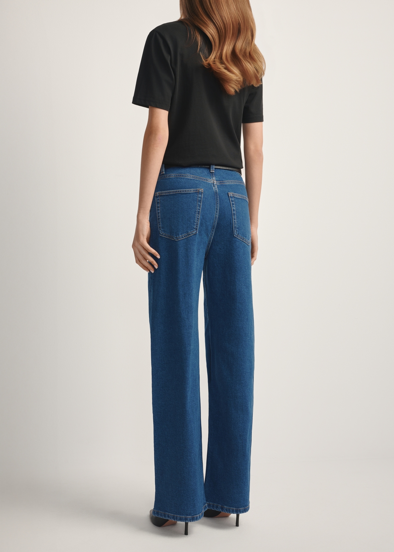 Dámske modré džínsové nohavice JEADT-0014-7H(W26), pohľad na modelku zozadu. Viditeľná polovica siluety.