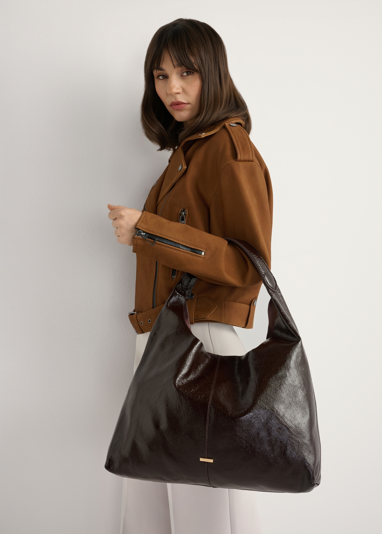 Veľká hnedá kožená dámska kabelka TORES-1179-1I(W26), pohľad na produkt na ramene modelky. Viditeľná polovica siluety.