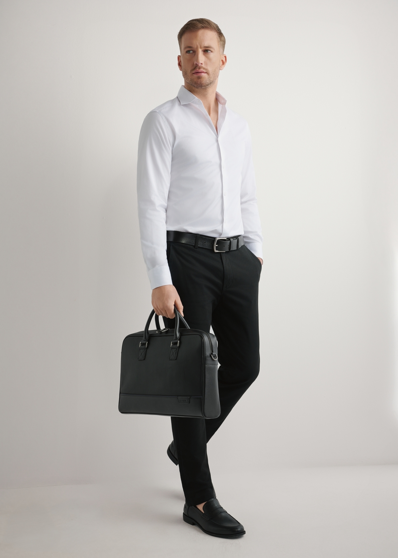 Čierna kožená taška na notebook TORMS-0494-99(W26) - mierne diagonálny pohľad na produkt, držaný v ruke modelky, na svetlom pozadí.