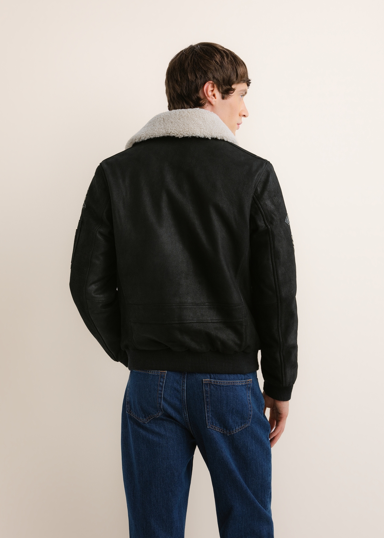 Čierna kožená bomber bunda KURMS-0423-99(Z26), pohľad zozadu na modelku. Viditeľná polovica siluety.
