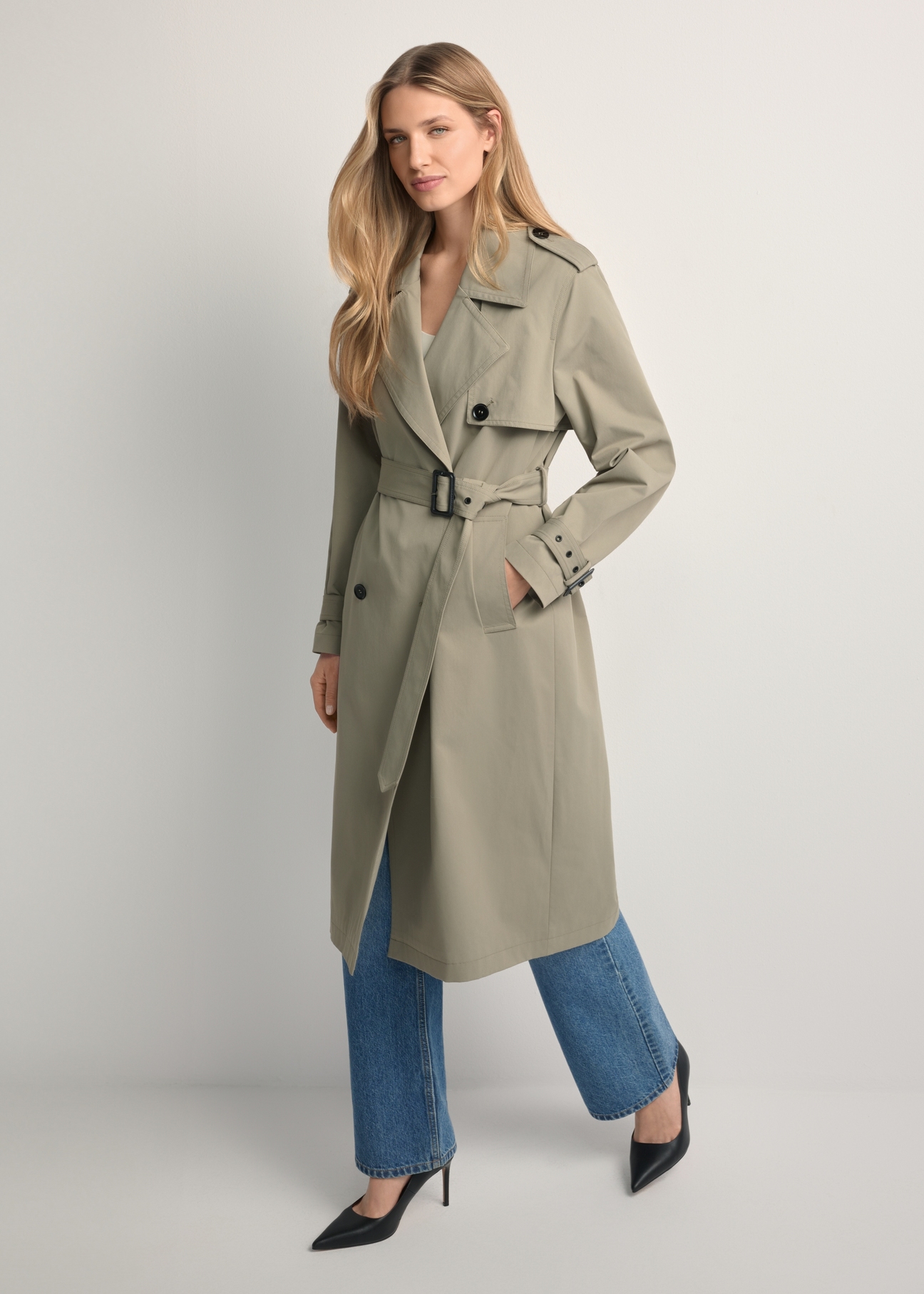 Dámsky kabát dlhej šalviovej farby KURDT-0512-8F(W26), pohľad spredu na produkt na modelke. Viditeľné celé telo.