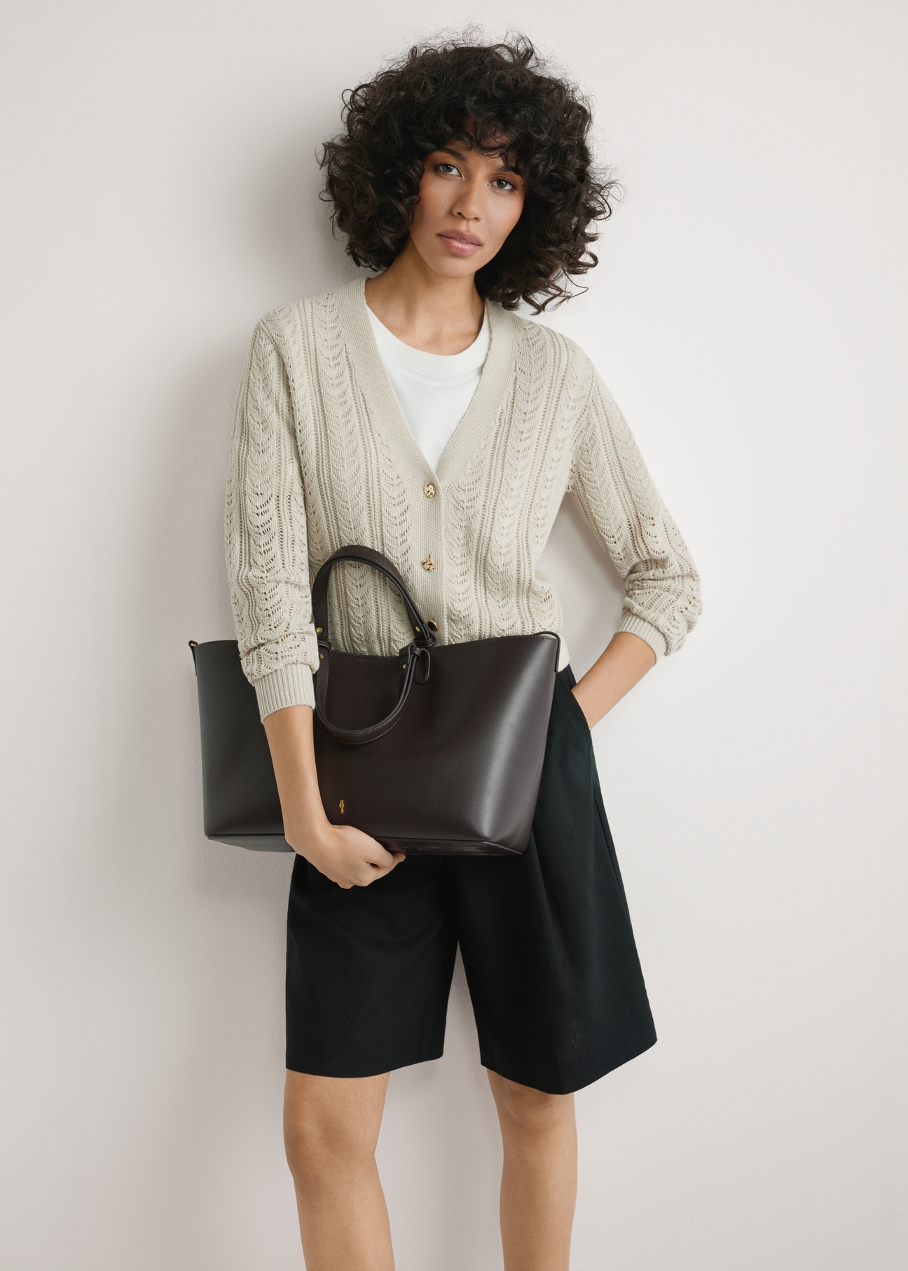 Hnedá dámska nákupná taška TOREC-1240-1H(W26), pohľad na produkt v rukách modelky. Viditeľná polovica siluety.