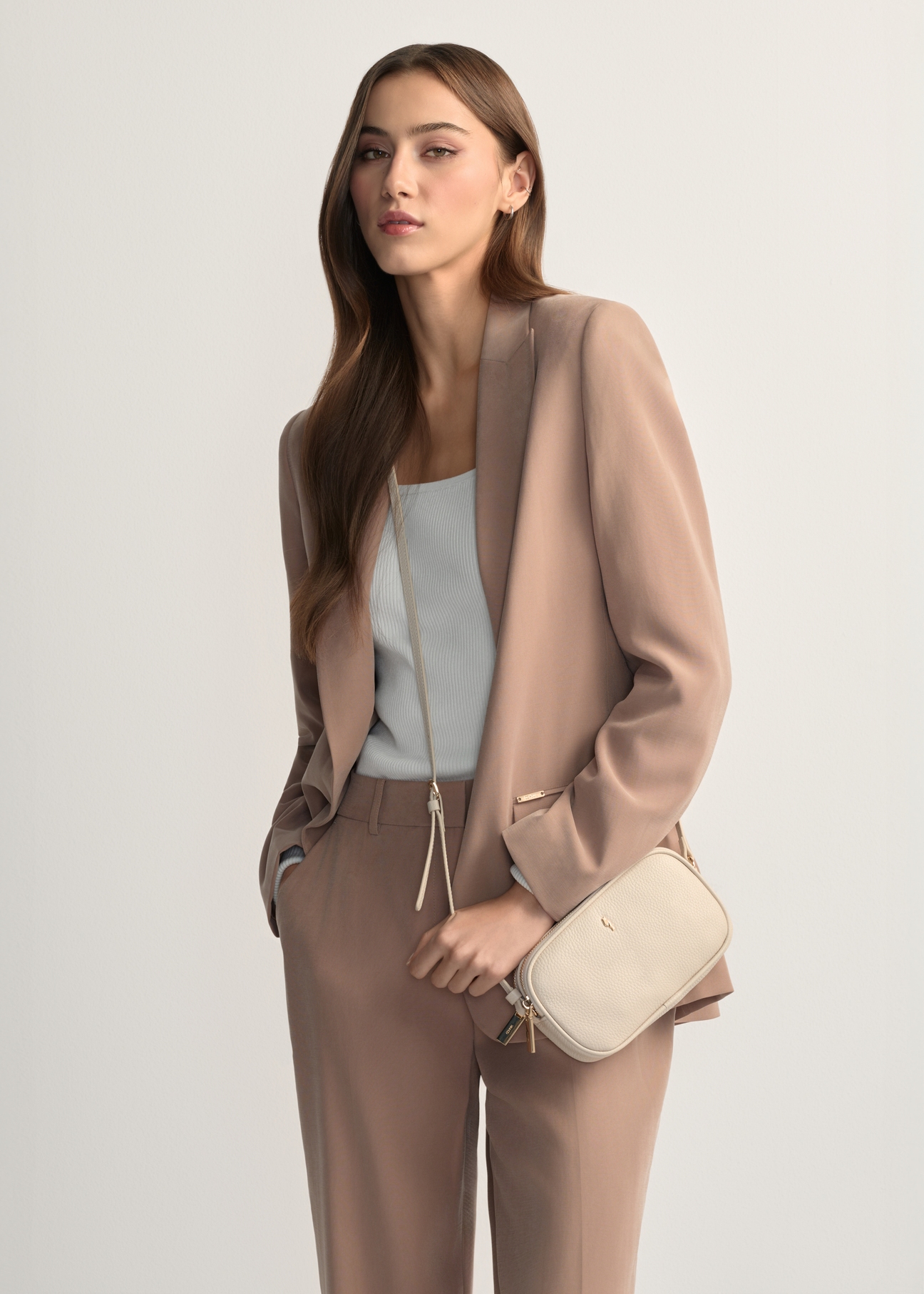 Malá dámska kožená kabelka v krémovej farbe TORES-1152-0B(W26), pohľad na produkt spredu na modelke, viditeľná polovica siluety.