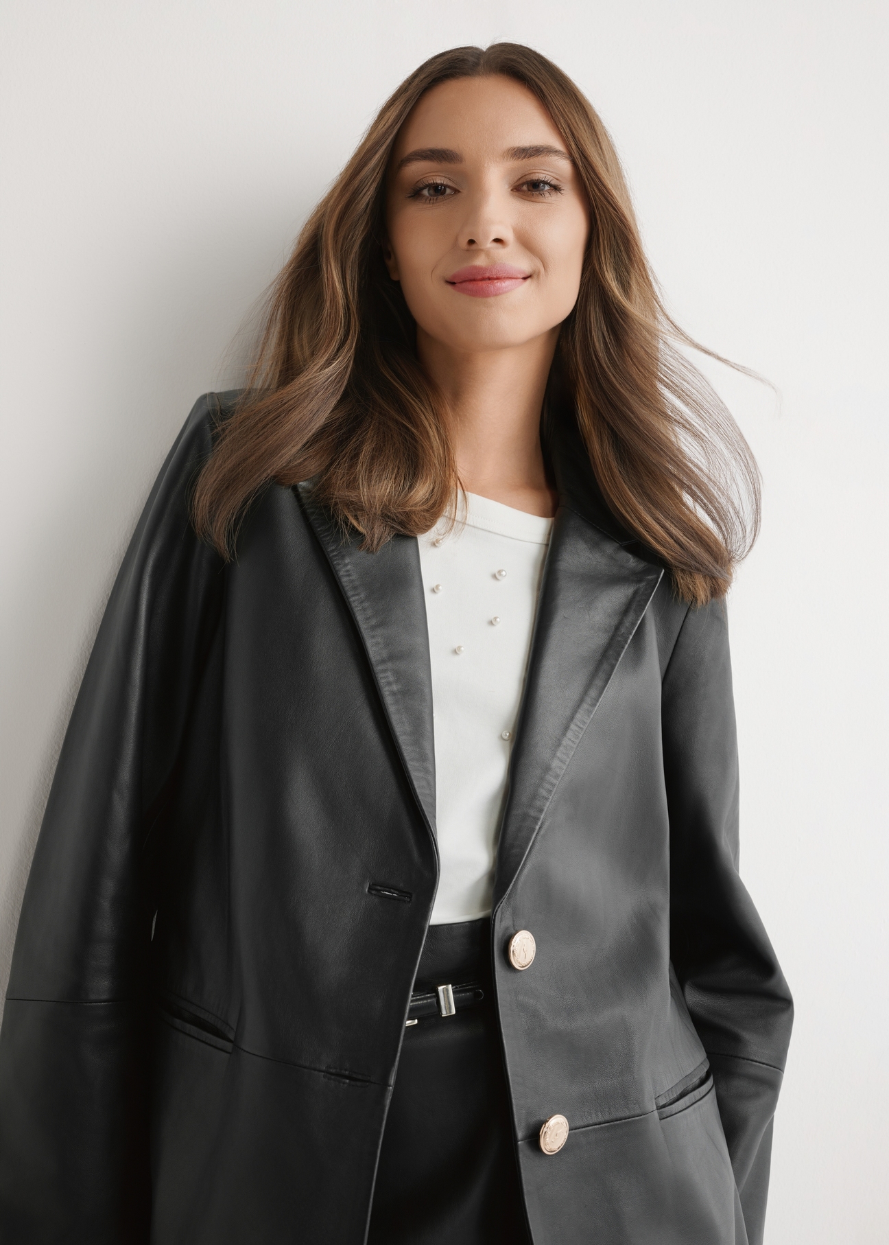 Dámska čierna kožená bunda KURDS-0606-99(W26) - pohľad spredu na výrobok, na modelke, na svetlom pozadí. Viditeľná polovica siluety.