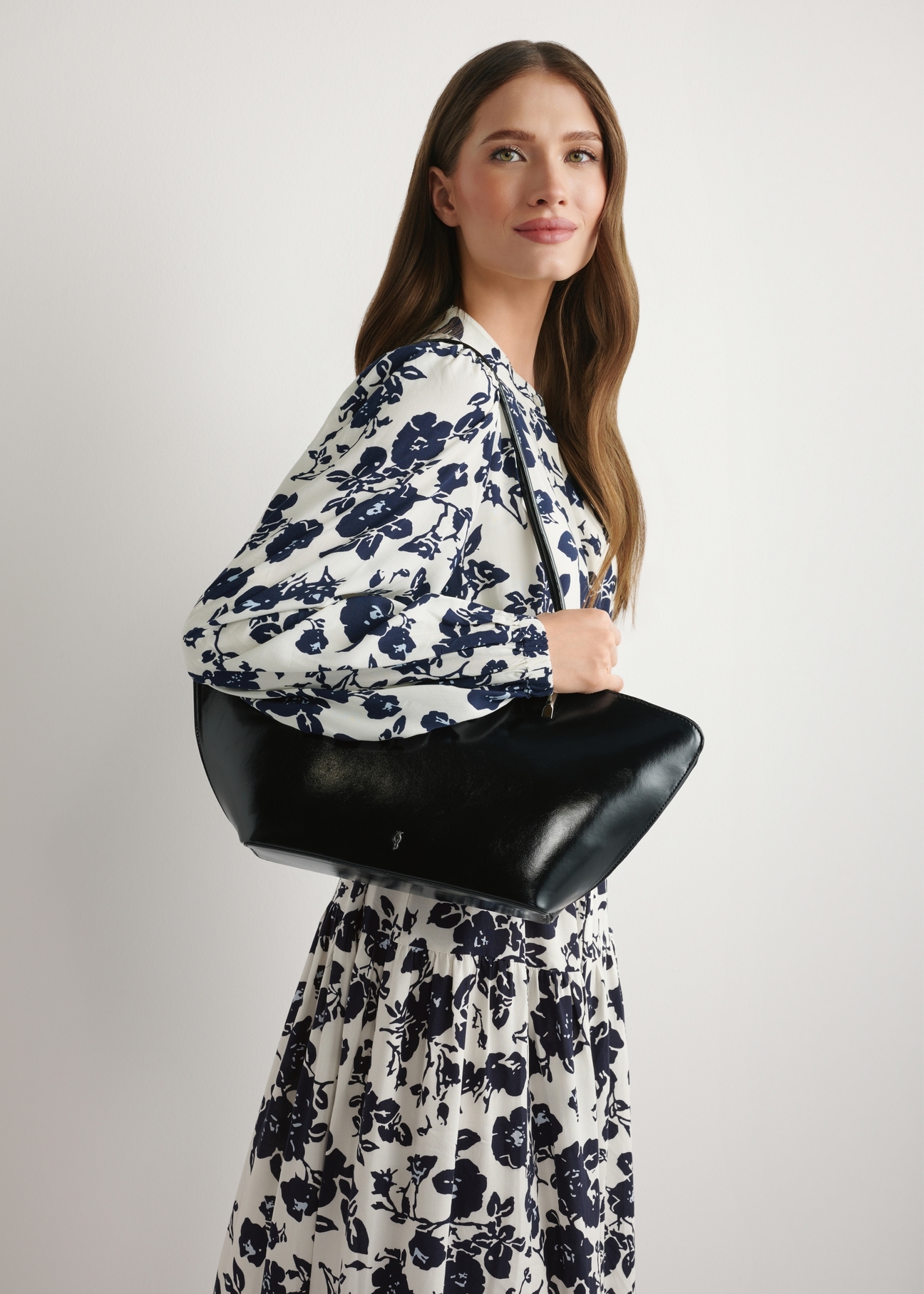 Čierna dámska kabelka cez rameno TOREC-1237-99(W26) - pohľad spredu na produkt, na modelke, na svetlom pozadí. Viditeľná polovica siluety.