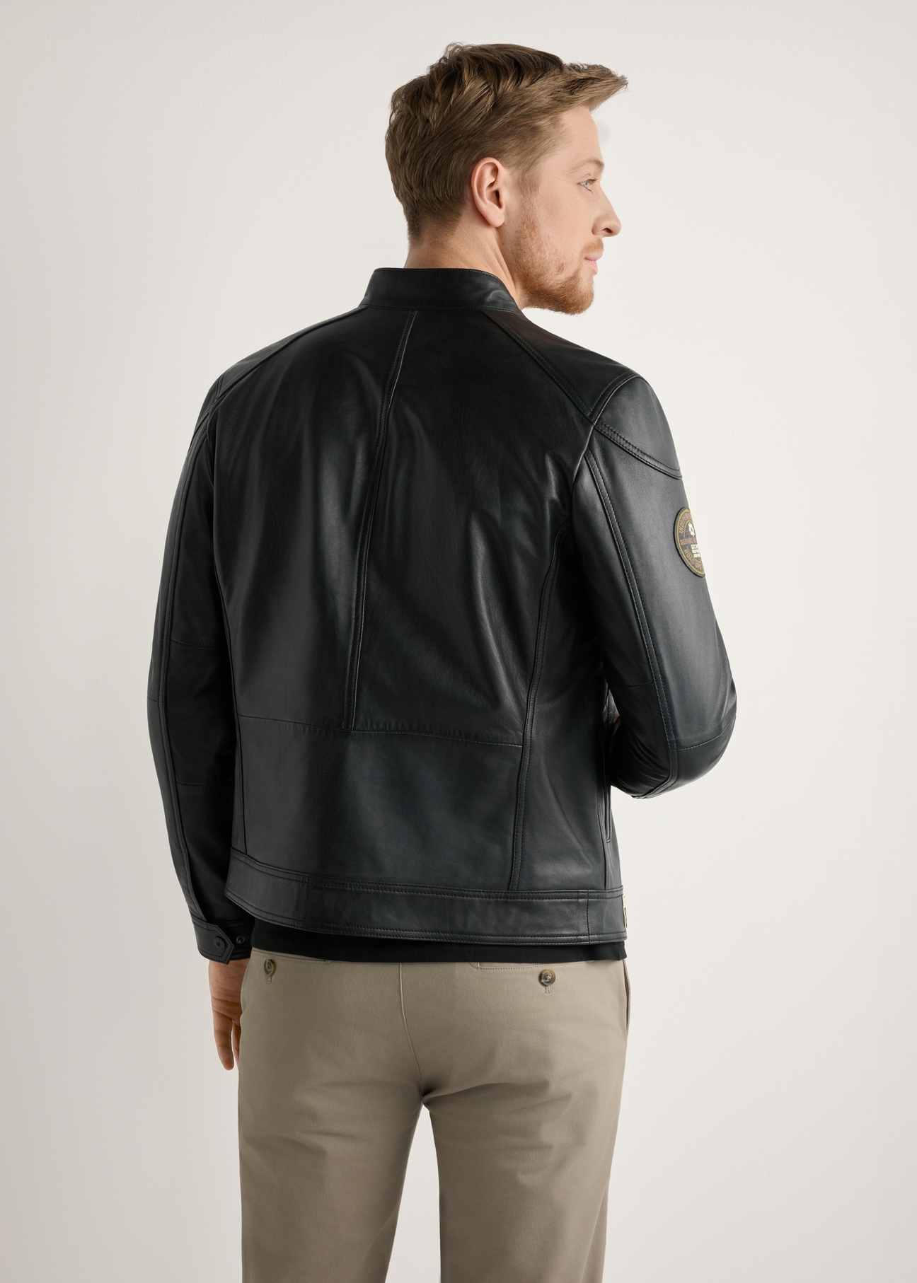 Pánska čierna kožená bunda KURMS-0301A-99(W26) - pohľad na výrobok zozadu, na modeli, na svetlom pozadí. Viditeľná polovica siluety.