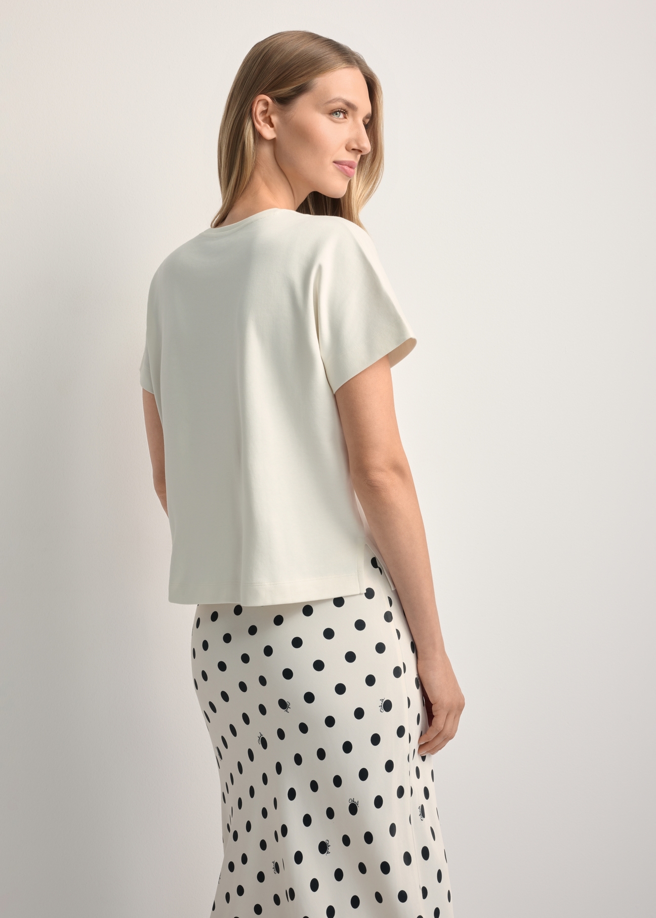 Dámske krémové tričko z mercerizovanej bavlny TSHDT-0154-0B(W26) - pohľad na výrobok zozadu, na svetlom pozadí. Viditeľná silueta po kolená.