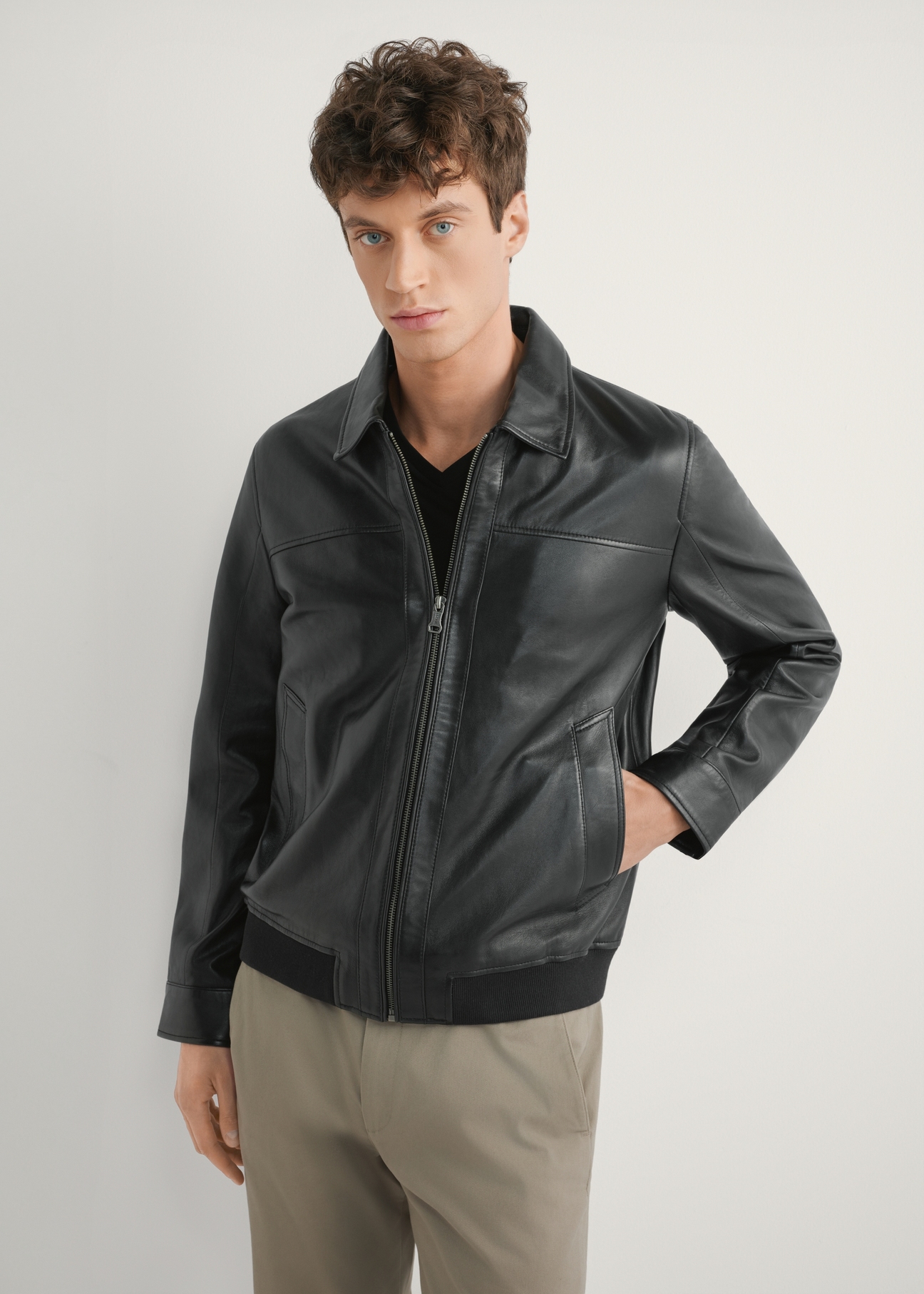 Čierna pánska kožená bunda KURMS-0407-99(W26), pohľad spredu na modelku. Viditeľná polovičná silueta.