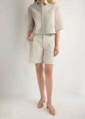 Dámske krémové kožené šortky SPODS-0047-0B(W26), pohľad spredu na produkt na modelke. Viditeľná polovica siluety.