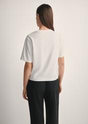 Dámske krémové bavlnené tričko TSHDT-0138-0B(W26), pohľad na produkt zozadu na modelke, viditeľná polovica siluety.