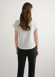 Dámske krémové tričko so zlatou potlačou TSHDT-0162-0B(W26), pohľad na produkt zozadu na modelke. Viditeľná polovica siluety.