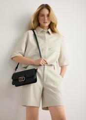 Čierna dámska taška cez rameno TOREC-1120-99(W26) - pohľad na produkt mierne diagonálny, na modelke, na svetlom pozadí. Viditeľná silueta po kolená.