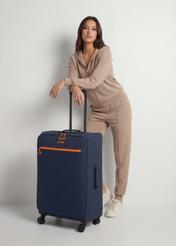 Veľký kufor na kolieskach WALNY-0045-7D-28(W26), diagonálny pohľad na produkt vedľa siluety modelky.