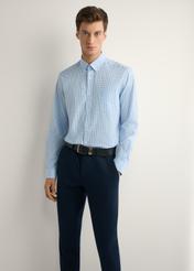 Pánska modrá kockovaná bavlnená košeľa KOSMT-0277-7B(W26), pohľad spredu na produkt na modelke. Viditeľná polovica siluety.