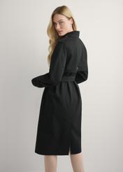 Dlhá čierna dámska bunda v podobe kabáta KURDT-0512-99(W25), pohľad na produkt zozadu na modelke, viditeľná polovica siluety.