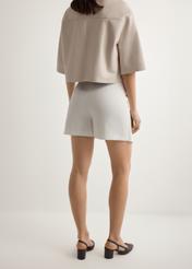 Dámske biele culottes SZODT-0008-0B(W26), pohľad na modelku zozadu. Viditeľná polovica siluety.