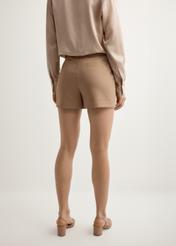 Dámske elegantné šortky v ťavej farbe SZODT-0018-1D(W26), pohľad zozadu na produkt na modelke. Viditeľná polovica siluety.