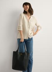 Veľká čierna dámska nákupná kabelka TOREC-1142-9I(W26), pohľad na produkt v ruke modelky. Viditeľné celé telo.