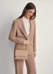 Béžová dámska kabelka s monogramom TOREC-1155-1A(W26), pohľad spredu na produkt na modelke, viditeľná polovica siluety.