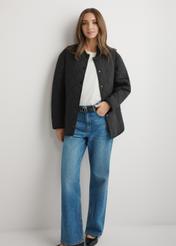 Dámska čierna prešívaná bunda KURDT-0580-99(W26) - pohľad spredu na výrobok, na modelke, na svetlom pozadí. Viditeľné celé telo.