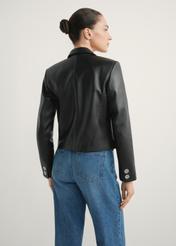 Dámska krátka kožená bunda KURDS-0522-99(W26) - pohľad zozadu na výrobok, na modelke, na svetlom pozadí. Viditeľná polovica siluety.