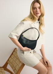 Malá čierna kožená dámska kabelka TORES-1263-99(W26) - pohľad spredu na produkt, ktorý drží modelka, na svetlom pozadí. Viditeľná silueta po kolená.