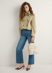 Dámsky stredne veľký batoh krémovej farby TOREC-0920-0B(W26), pohľad na produkt v ruke modelky. Viditeľné celé telo.