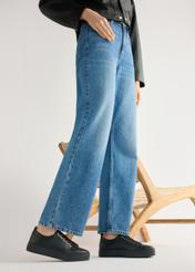 Dámske čierne kožené tenisky BUTYD-1062-99(W26) - bočný pohľad na produkt, na modelke, na svetlom pozadí. Viditeľná silueta po kolená.