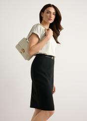 Malá dámska krémová kabelka TOREC-1186-0B(W26) - pohľad na produkt mierne diagonálny, na modelke, na svetlom pozadí. Viditeľná silueta po kolená.